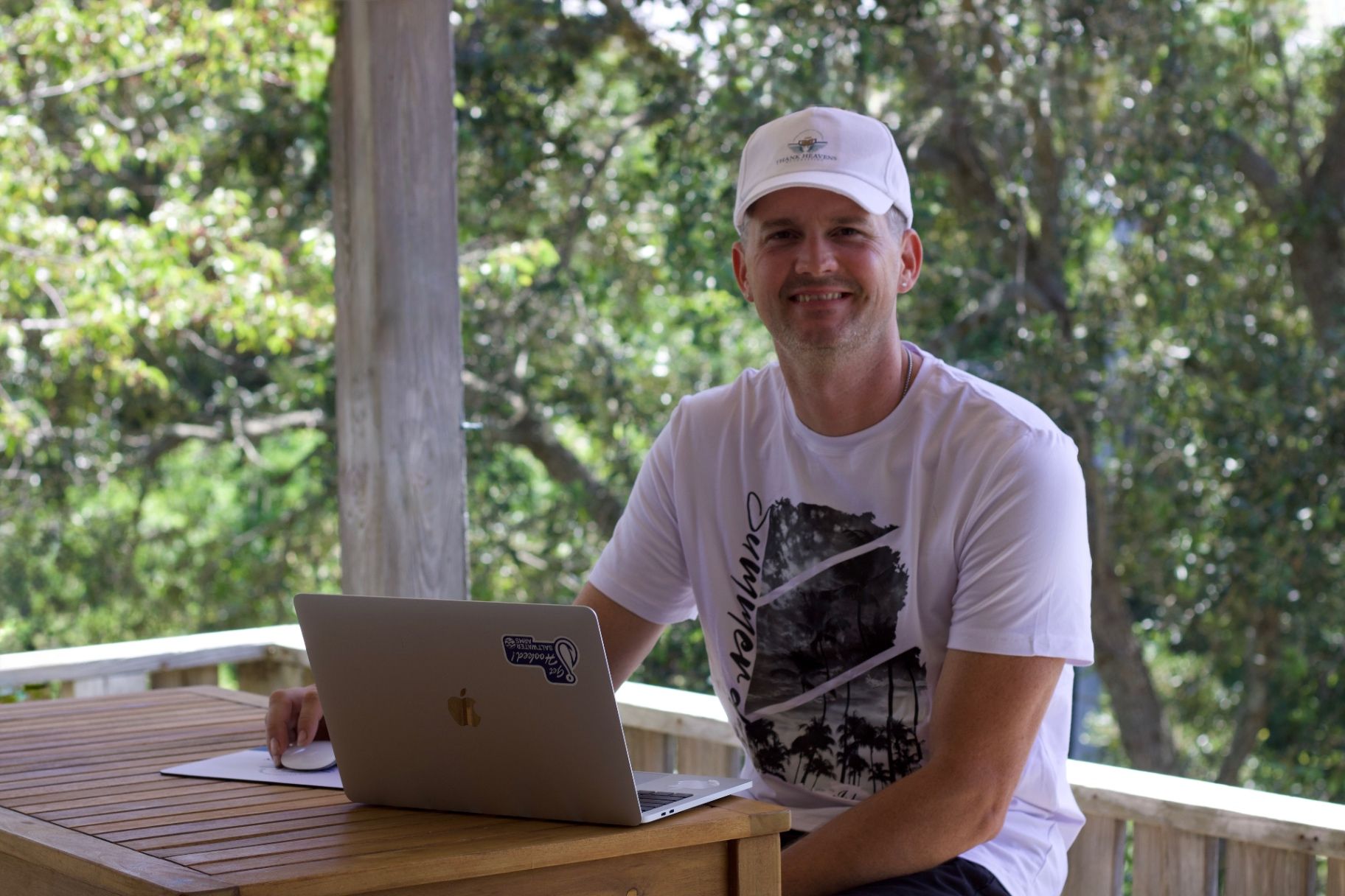 Joshua seated outdoors at a table with his laptop